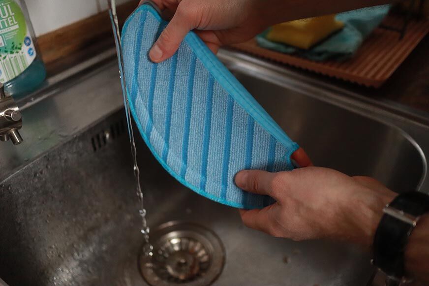 Der Wischmopp des Yeedi Vac Hybrid wird unter fließendem Wasser angefeuchtet